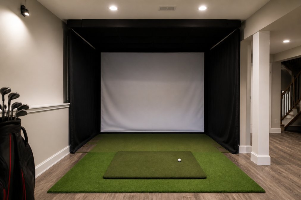 Residential basement converted into a compact golf simulator bay with EasySim enclosure, hitting mat, and impact screen installed, showing how a small 10x8 room transforms into a functional practice area with proper lighting