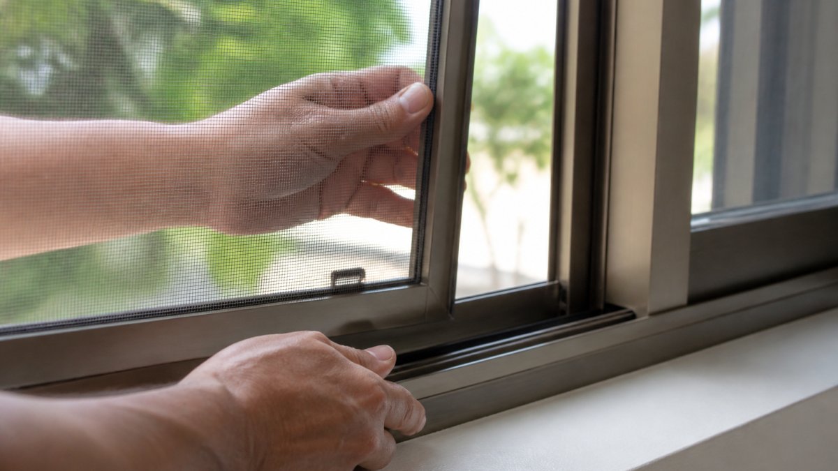 Hands pressing a window screen into a metal frame screen channel without tools