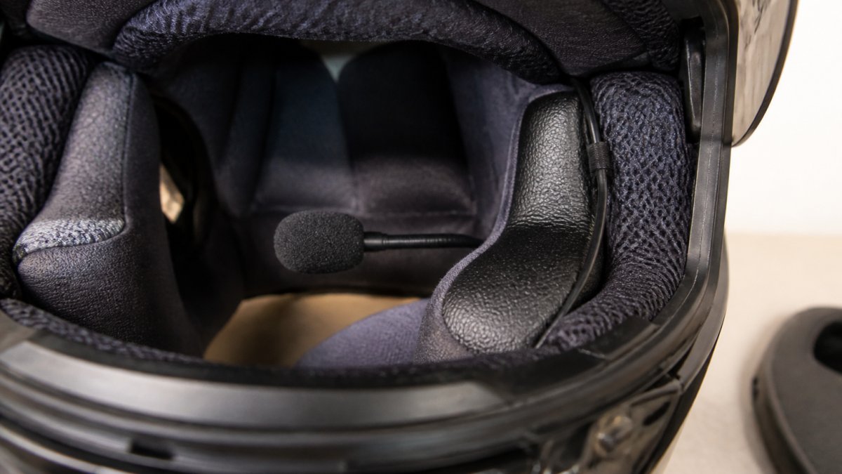 Diagram showing proper microphone placement and wire routing inside a full-face motorcycle helmet lining.