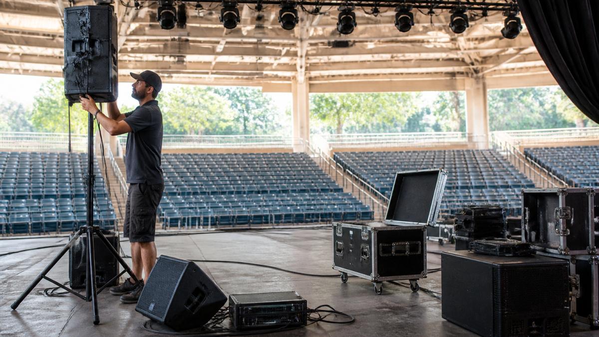Technician adjusting a speaker for a sound and lighting system on a concert stage