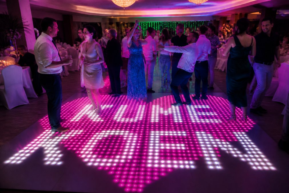 Professionele LED dansvloer in feestzaal met kleurrijke lichteffecten in blauw, paars en groen, gasten dansend in festive sfeer