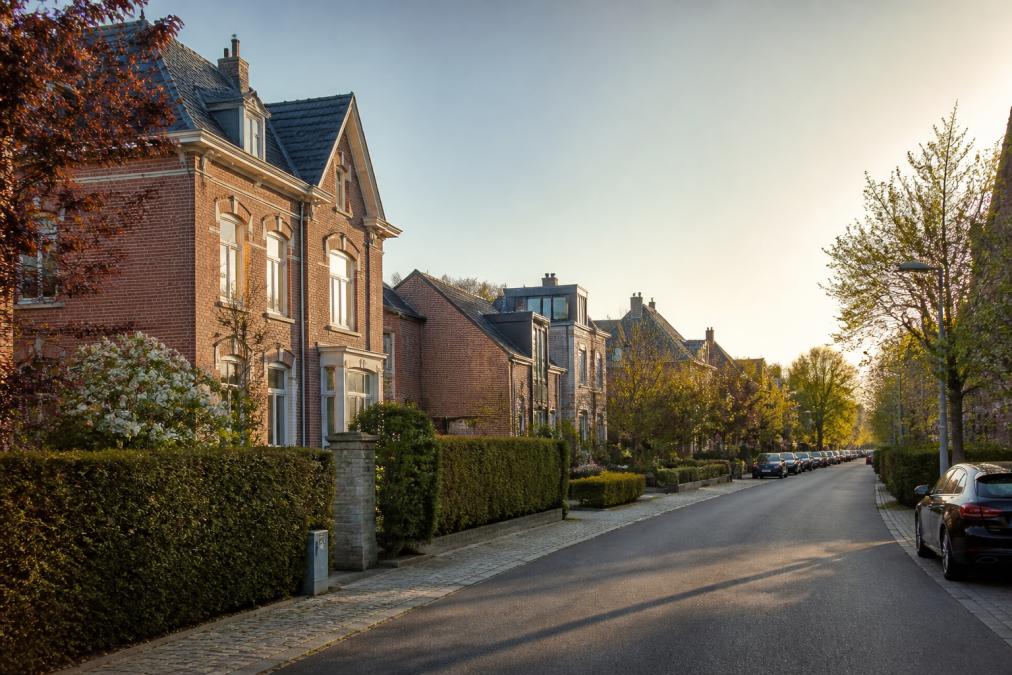 Rue résidentielle calme à Waterloo avec des maisons de standing en briques, arbres matures et voitures discrètement garées, lumière douce de fin d'après-midi