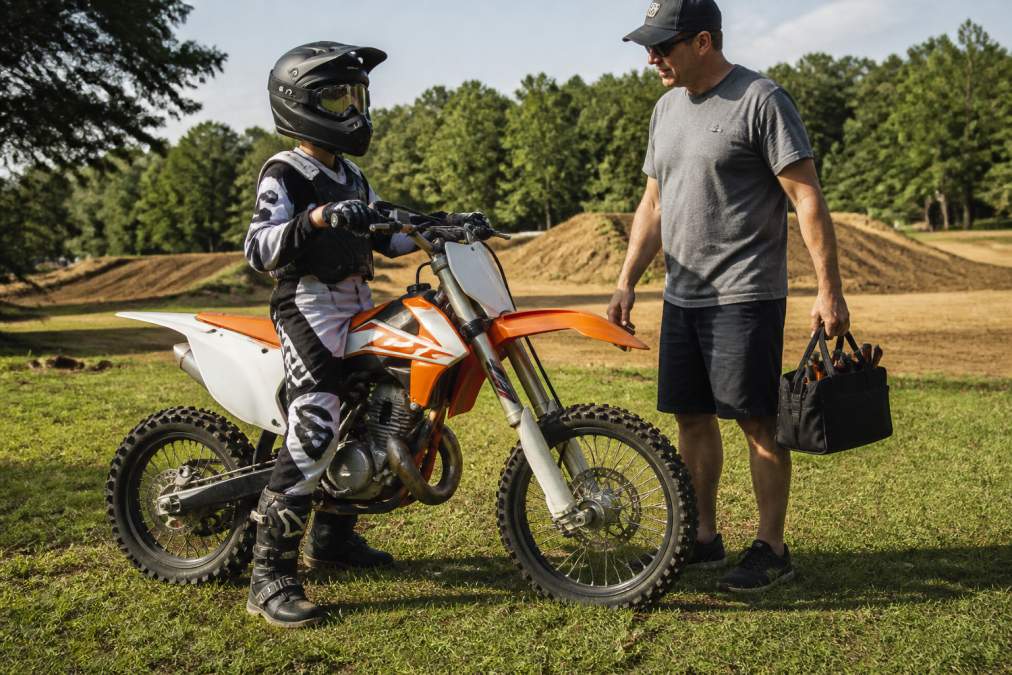 13-year-old rider on an 85cc dirt bike with a parent, ready to start motocross at the track