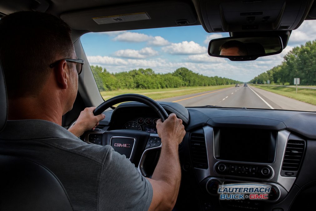 Driver's hands on steering wheel during calm highway driving with clear road ahead, representing mindful acceleration and fuel-efficient driving technique