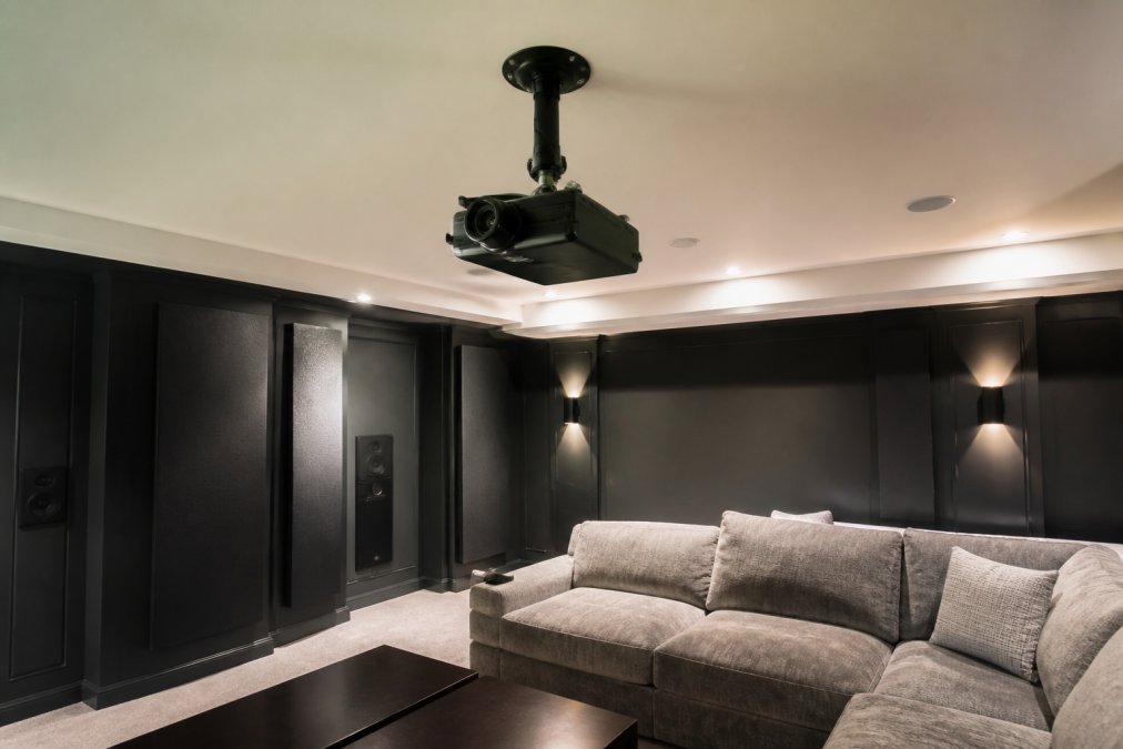 Dedicated home theater with projector on rotating stand mounted to ceiling, showing flexible positioning for both wall and ceiling projection angles, modern media room setup