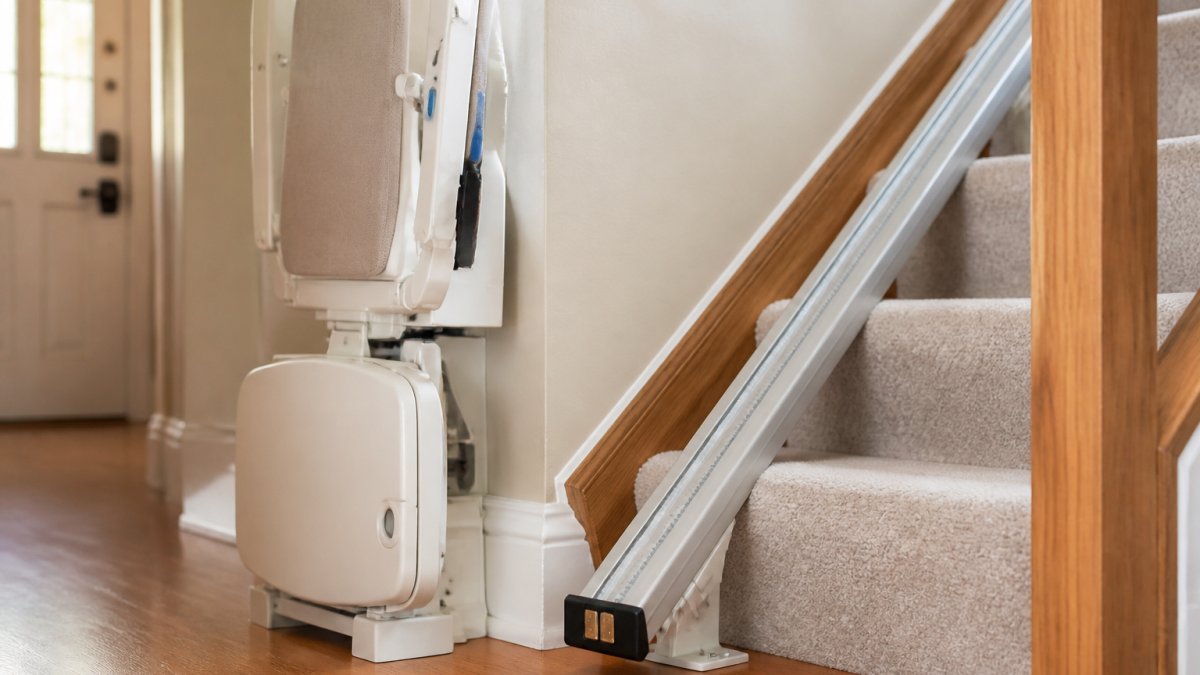 Stairlift parked at the base of a staircase with charging contacts aligned to maintain battery backup readiness