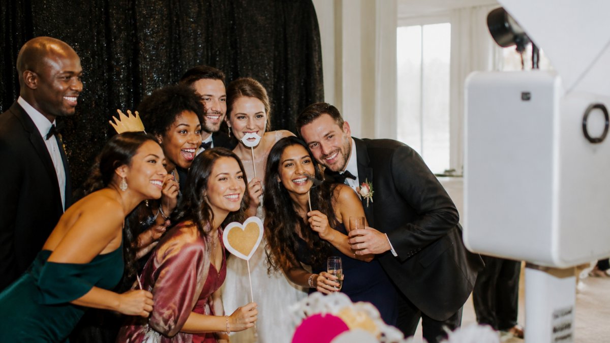 Wedding guests laughing and posing at a glam photo booth worth every moment of social engagement and joy.