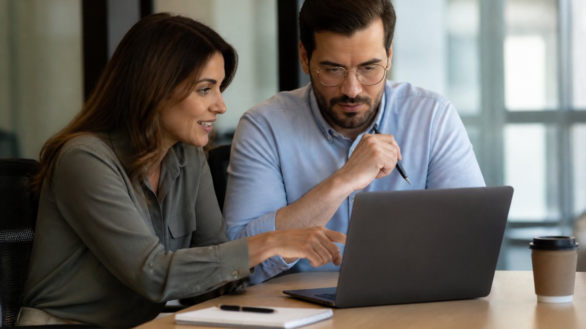 Sales manager and rep reviewing AI sales coaching dashboard on a laptop at a bright office desk