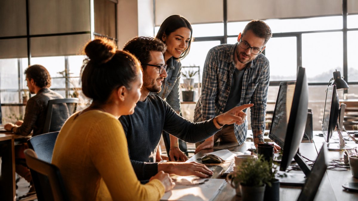 Is AI Web Design Worth It for Small Agencies? Small agency team collaborating on website layouts to determine if AI web design is worth it for small agencies
