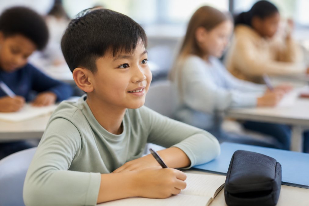 A school-aged child wearing MiSight contact lenses during a classroom activity, demonstrating practical daytime use without glasses or visible optical devices