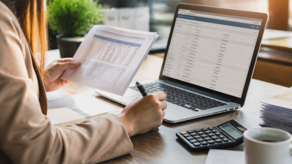 Accountant comparing bank statements with software for automated fraud detection during the reconciliation process