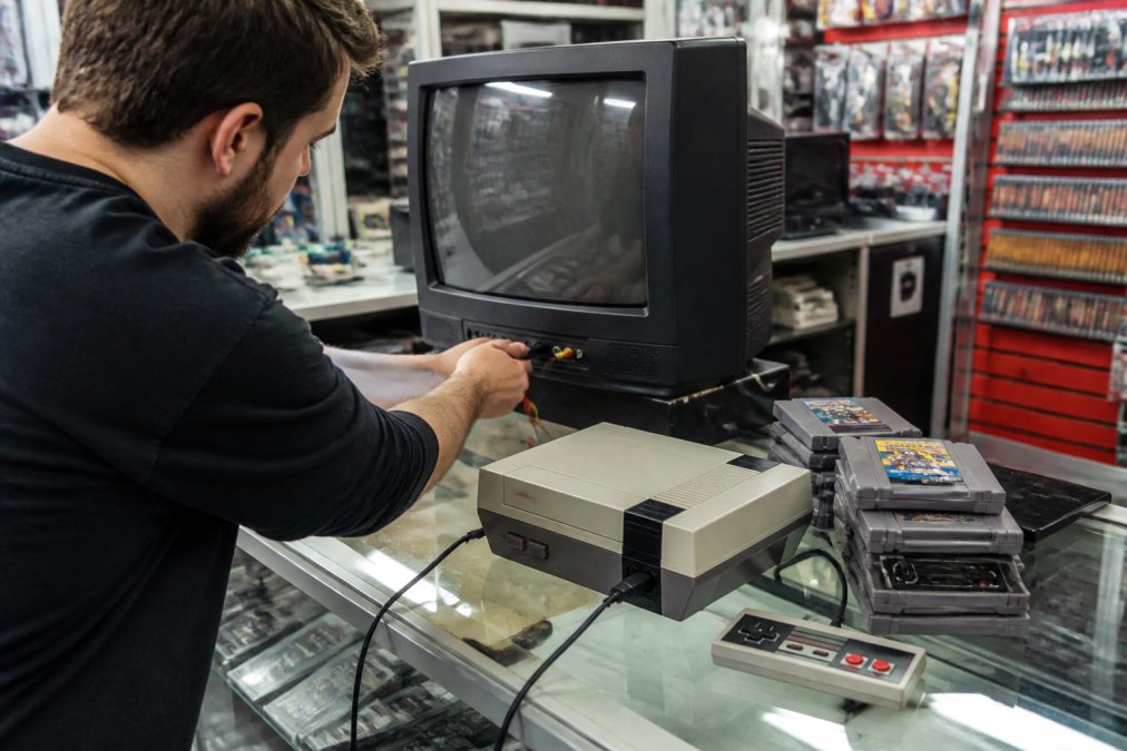 Customer testing refurbished retro consoles on a CRT television in a store