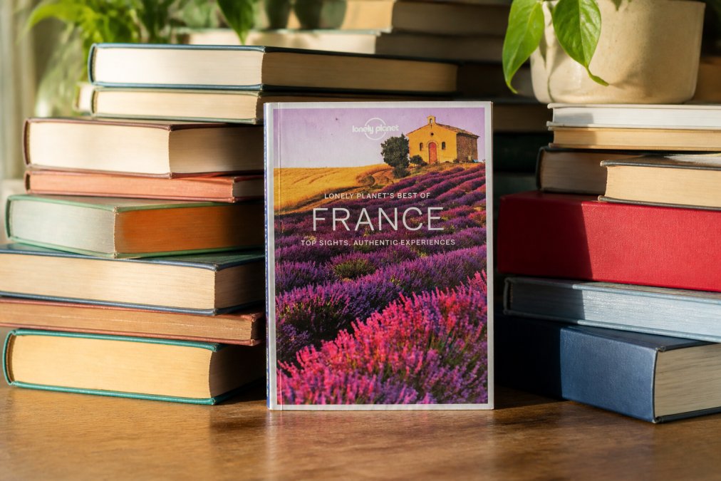 Stack of well-preserved second-hand books arranged thoughtfully on a wooden surface, with natural morning light illuminating the spines and covers, showing varied titles and genres ready for their next readers