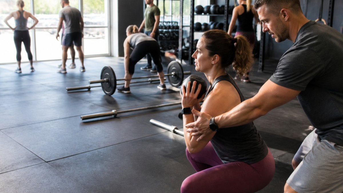 Diverse adults training in a CrossFit gym with a coach, illustrating if is crossfit worth the monthly cost for beginners.
