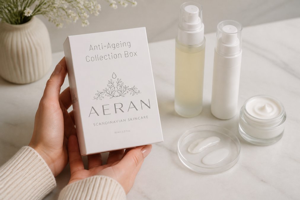 Close-up of hands holding a luxury skincare bottle with serums and moisturizers displayed on a clean white surface, showing product texture and formulation details