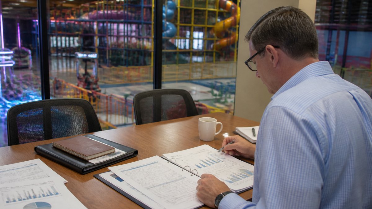 Business owner analyzing financial data to determine FEC consulting worth inside an entertainment center office.