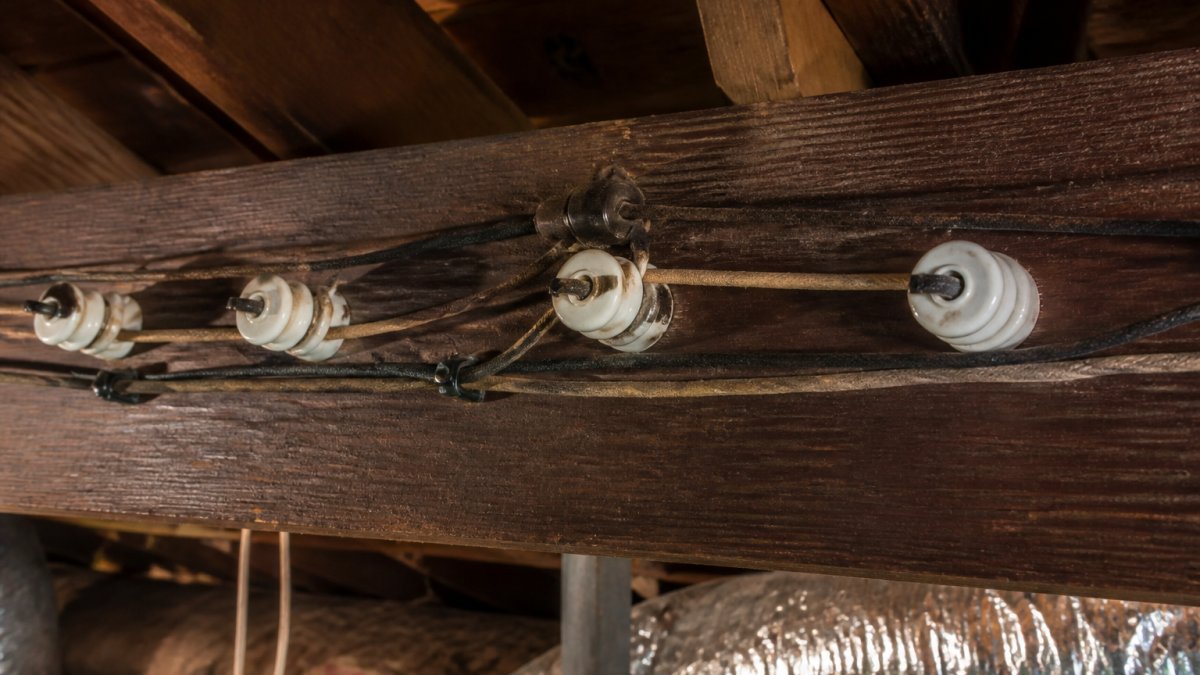 Diagram of knob and tube wiring components featuring ceramic knobs and cloth-wrapped wires installed on attic joists