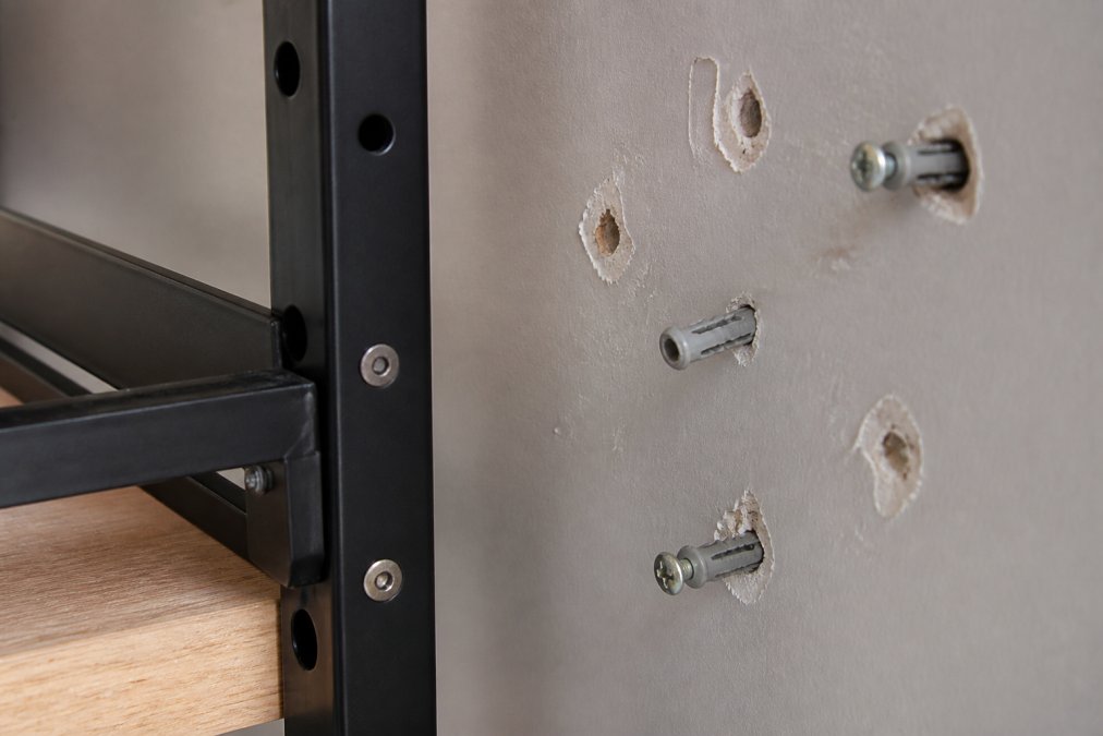 Close-up of modular shelving hardware and wall anchors showing wear marks and damage from repeated installation and removal in natural lighting