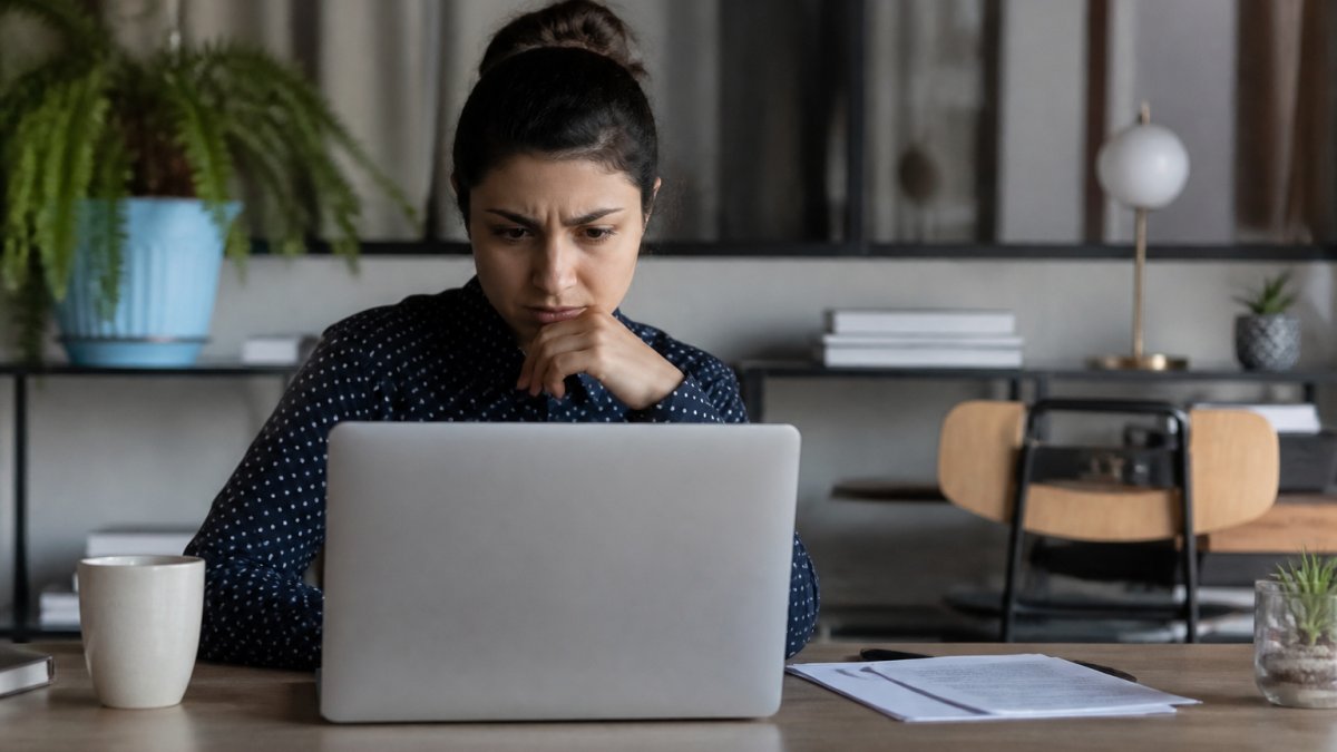 Concerned person using a laptop at a desk to search for personal information sold online.