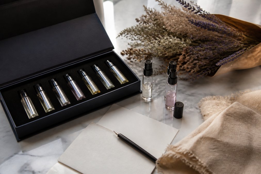 Curated narrative fragrance discovery set with sample vials, dried flowers, and a handwritten note on marble.