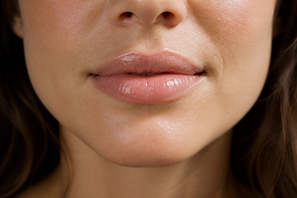 Close-up of woman's lips showing smooth, hydrated texture with natural glow after applying lip balm in natural daylight