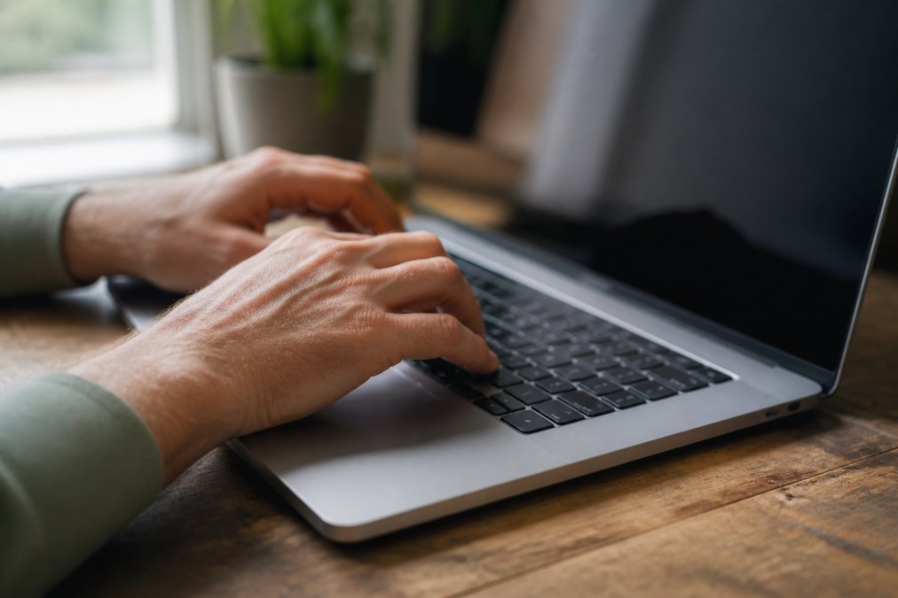 Close-up of hands typing a password on a laptop keyboard with a digital security padlock icon displayed on the screen, showing encrypted connection symbols
