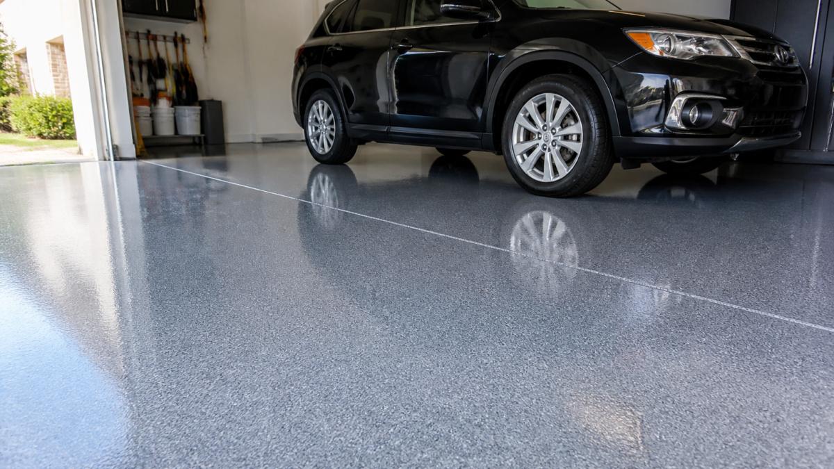 Professional epoxy garage floor with glossy finish and vibrant color, freshly coated concrete surface with vehicle parked on it, natural light highlighting durability and cleanliness