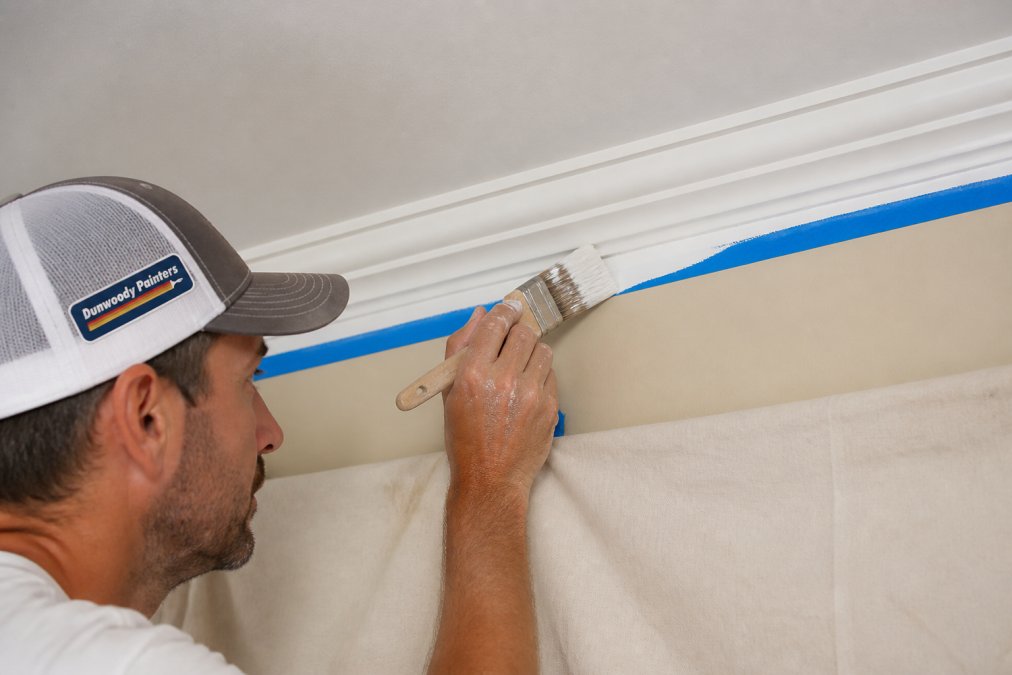 Professional painter using a brush to create a crisp edge for professional painting along a ceiling line.