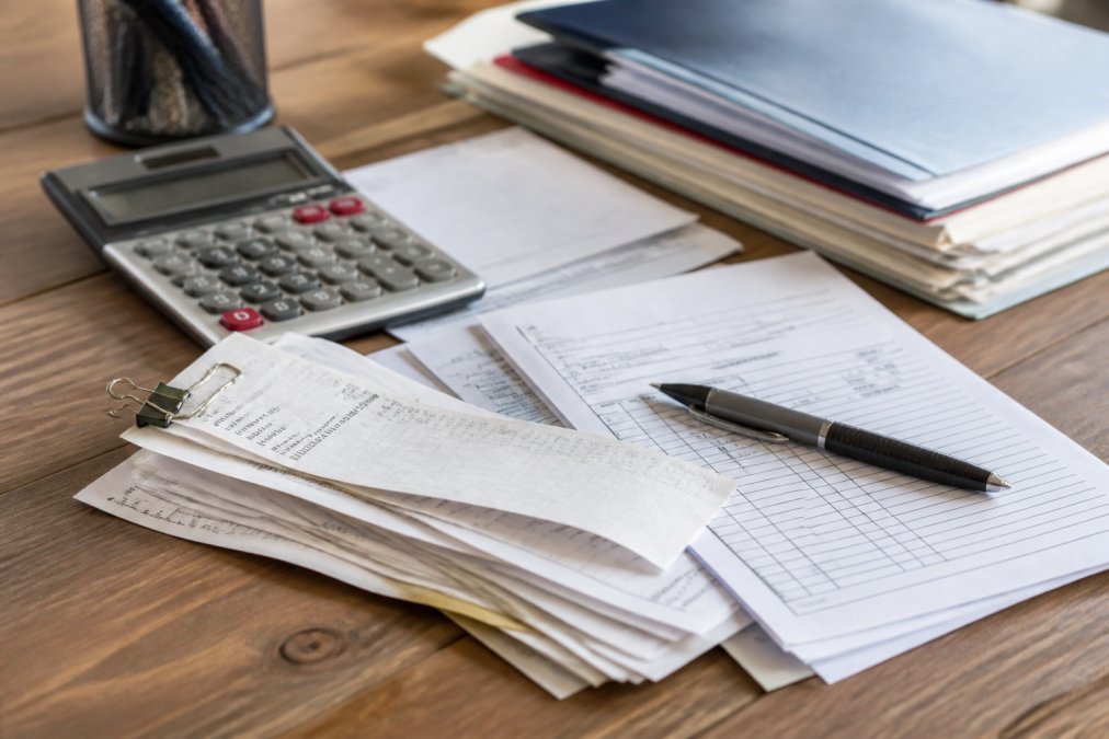 Close-up of organized pest control receipts, invoices, and documents spread on a desk with a pen and calculator nearby