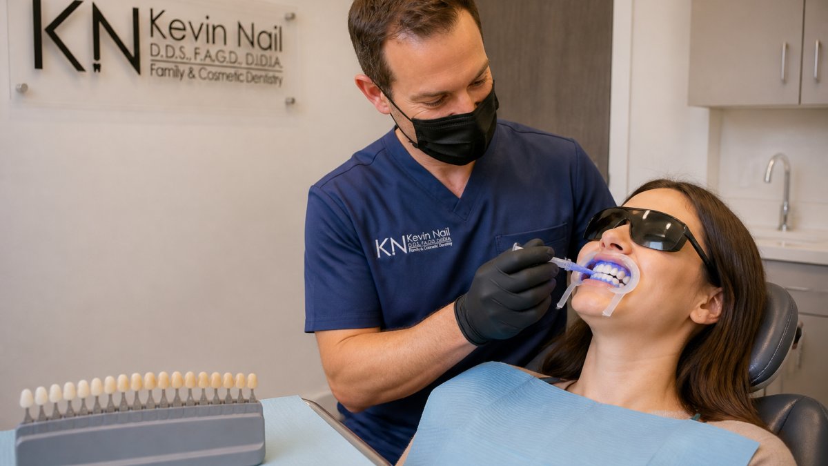 Dental hygienist applying professional teeth whitening gel to a patient using a shade guide in a dental office