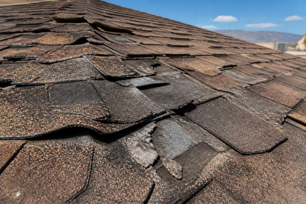 Close-up of deteriorated roof shingles showing curling edges, missing pieces, and weathered surfaces from intense sun exposure and desert heat in El Paso