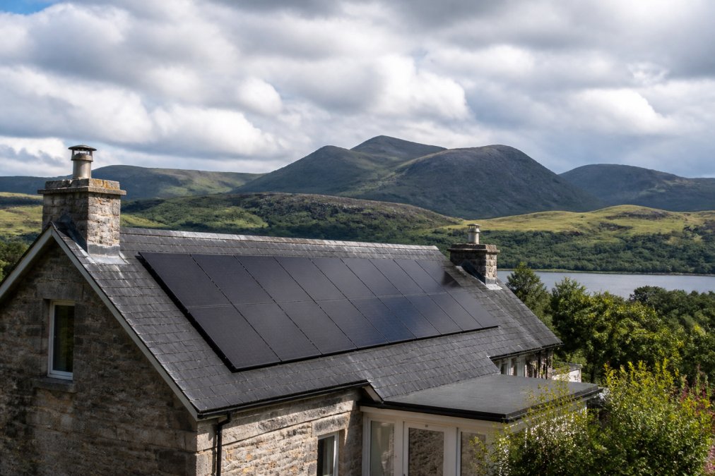 Solar panels installed on a stone house in Scotland, showing if is solar worth it in Scotland despite cloudy weather