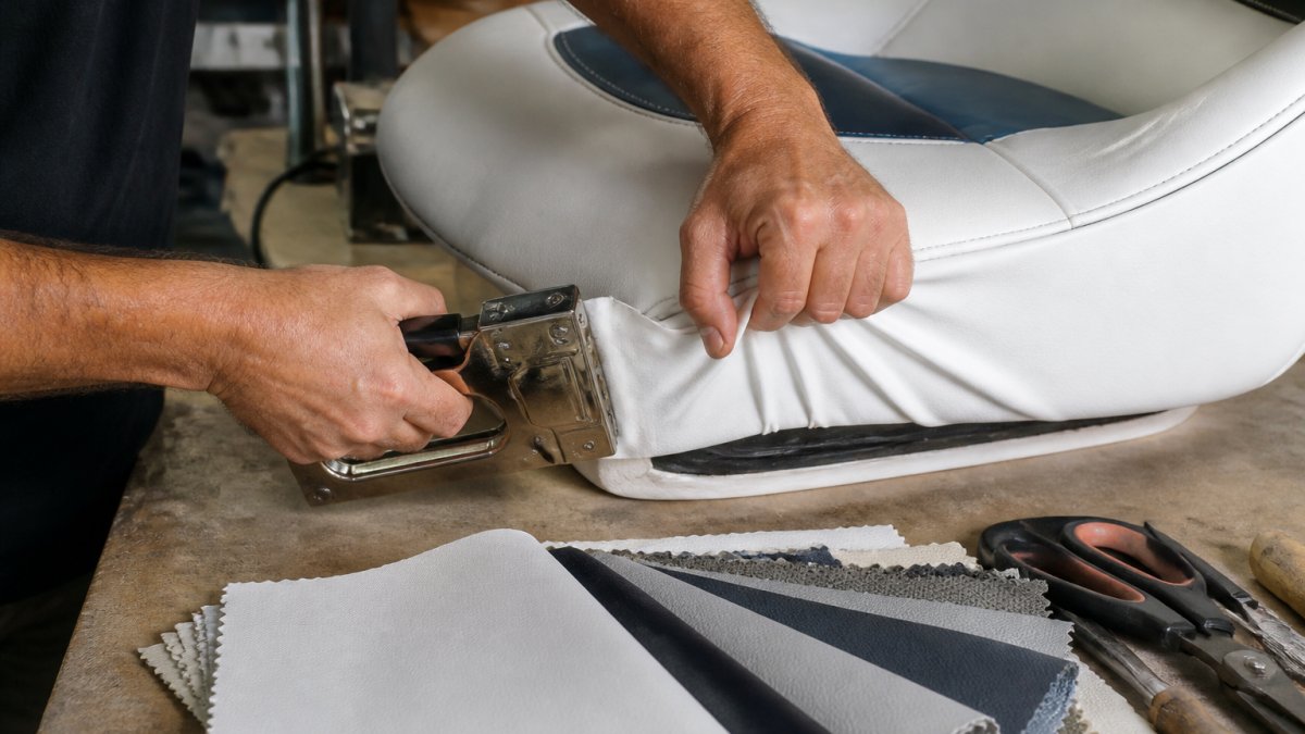 Marine upholsterer stretching vinyl over a boat seat to streamline upholstery work on a workbench