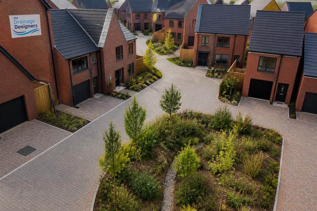 Aerial view of a compact new-build housing development showing permeable driveways and landscaped rain gardens integrated between the homes