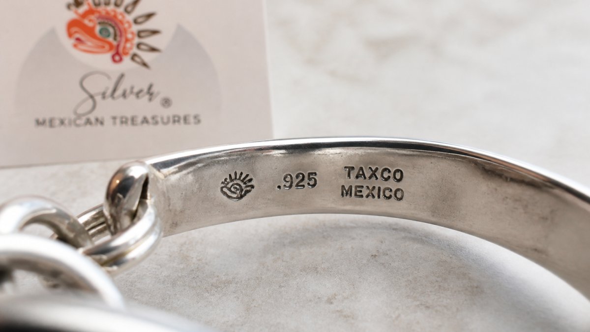 Close-up of sterling silver jewelry piece showing the .925 hallmark and maker's mark clearly stamped into the metal under natural light, with fine detail visible in the stamped impressions