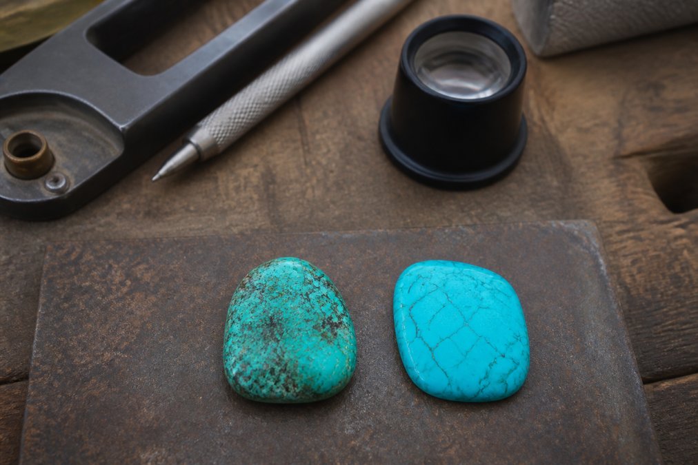 Close-up of authentic natural turquoise stone with irregular color variation, natural veining, and organic surface texture displayed next to uniformly dyed synthetic turquoise under natural daylight