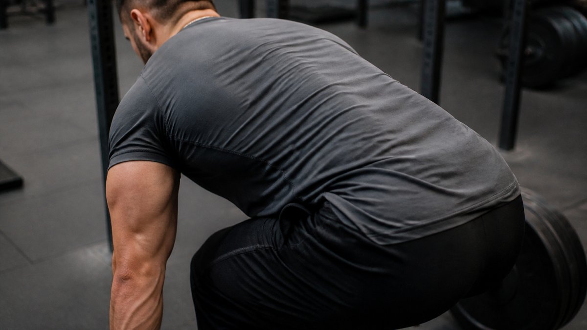 Diagram illustrating key fit features of a heavyweight gym shirt during a heavy barbell deadlift setup