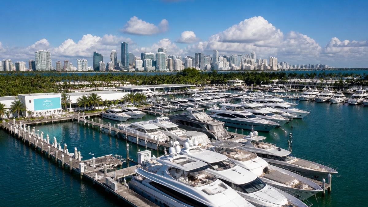 Aerial view of Island Gardens Marina showing moored luxury yachts with Miami skyline visible in the background during daytime