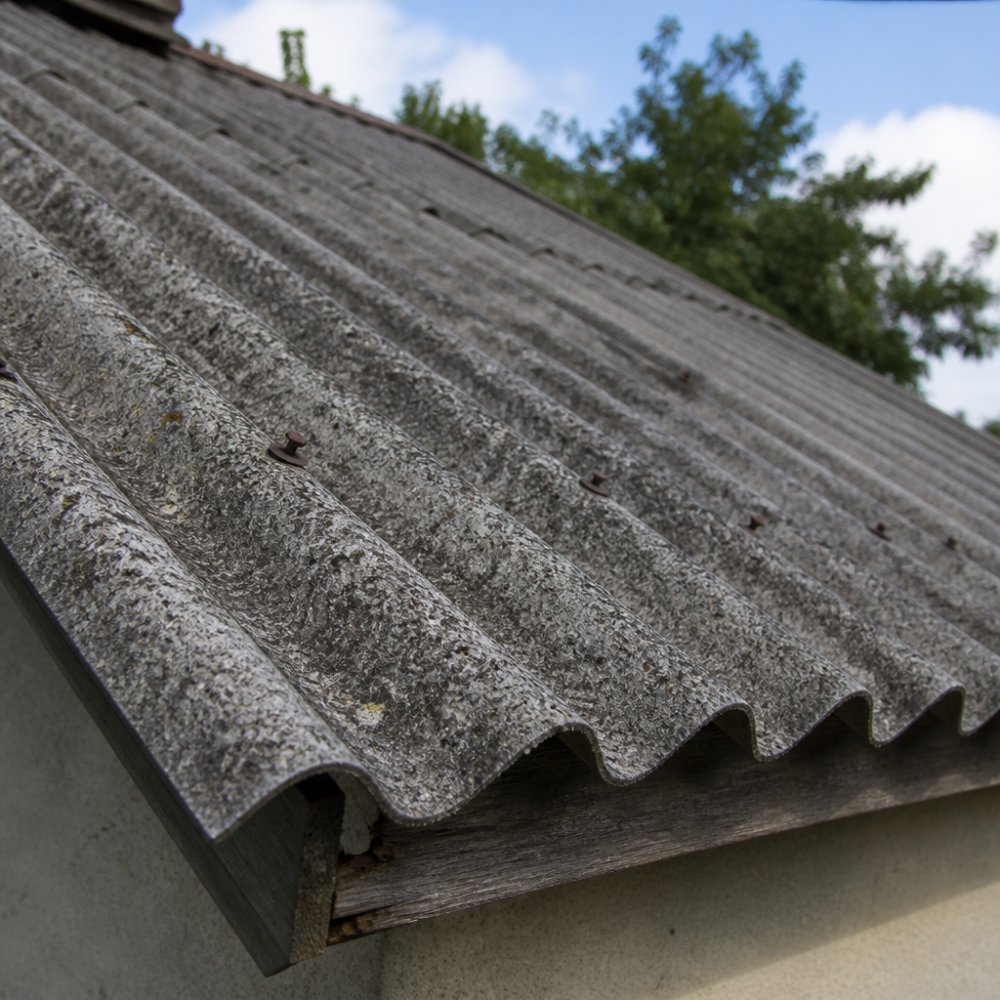 Detailní záběr na starou vlnitou eternitovou krytinu na rodinném domě, šedé desky s hrubým povrchem, denní světlo, pohled na strukturu materiálu