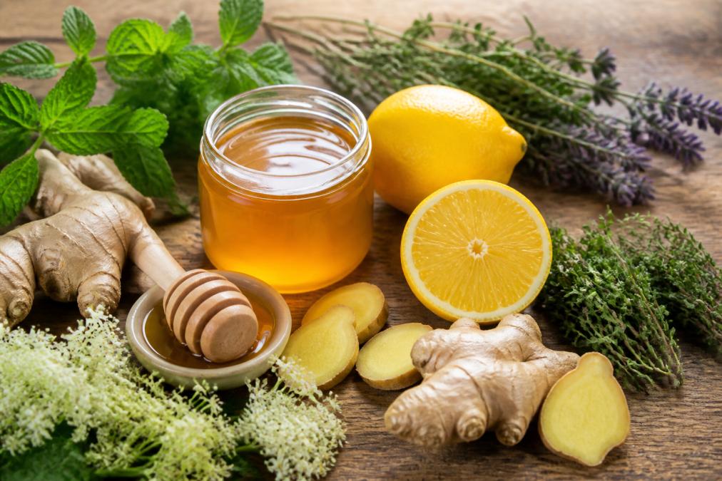 Svježi đumbir, med i limun na drvenom stolu kao sastojci za prirodni sirup za imunitet obasjani toplom prirodnom svjetlošću.