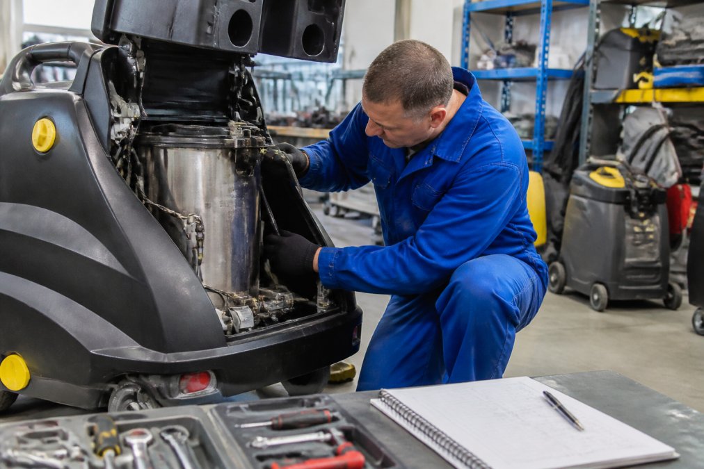Kärcher Commercial Steam Cleaner Alternative for 2026 1 A maintenance technician in blue overalls inspecting the boiler tank of a commercial steam cleaner in a well-lit workshop, with tools and a service logbook on a nearby bench