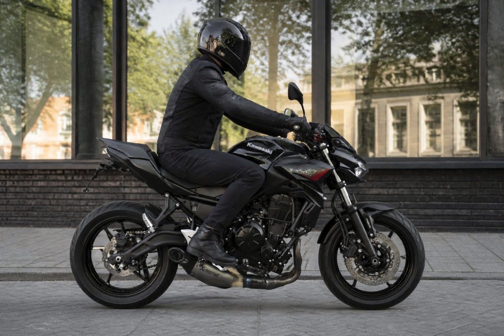 Rijder zittend op een Kawasaki Z650 in sportieve houding met focus op zithoogte en frameconstructie in daglicht, motorfiets geparkeerd in stedelijke omgeving