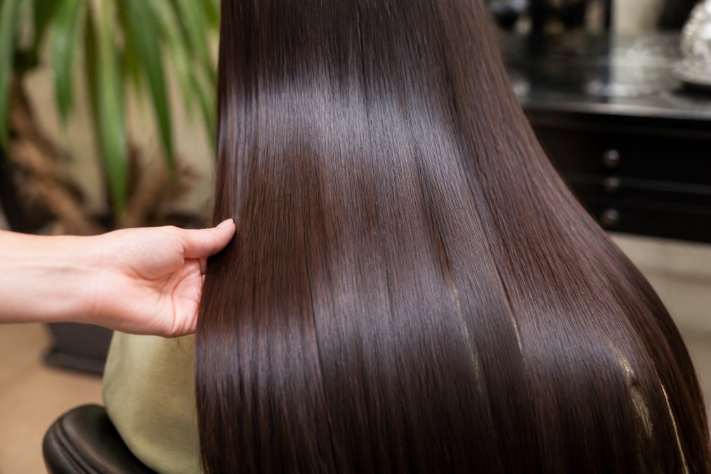 Close-up of smooth, glossy hair with a radiant shine after keratin treatment, showing individual strands with frizz-free texture under soft natural lighting