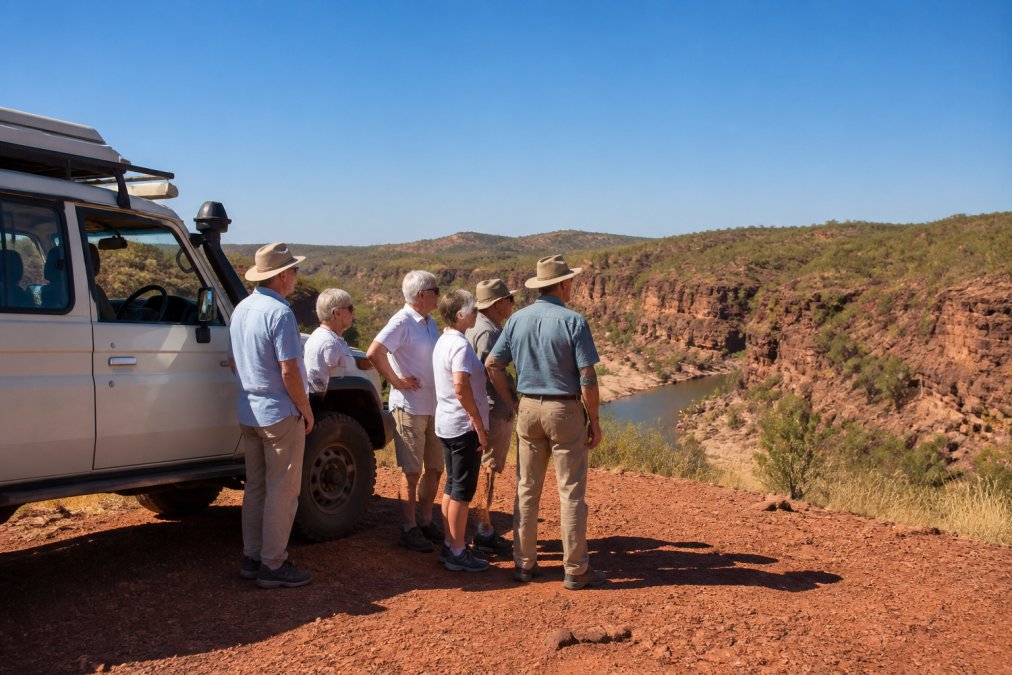 Mature travellers on Kimberley seniors tours standing by a 4WD vehicle near a rugged gorge under a blue sky