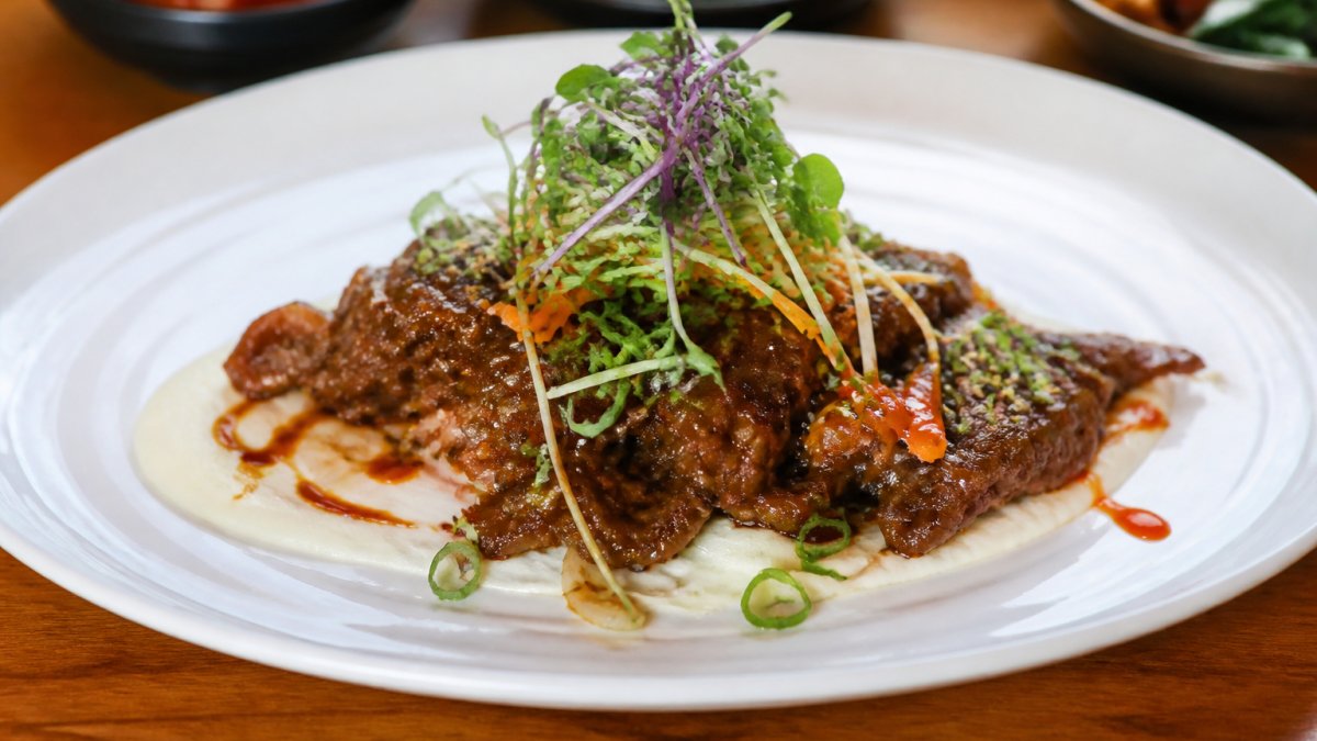 Close-up of a beautifully plated Korean fusion dish featuring bulgogi with modern presentation, garnished with microgreens and contemporary plating techniques on a white ceramic plate