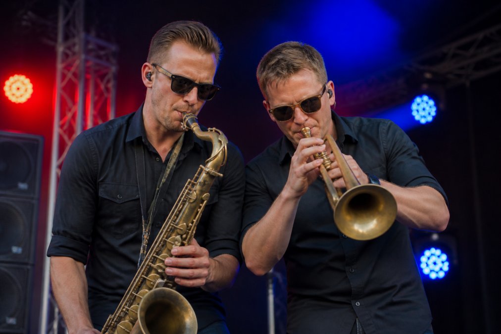 Muzikanten spelen saxofoon en trompet op een podium met sfeervolle verlichting bij de kosten live muziek bedrijfsfeest.
