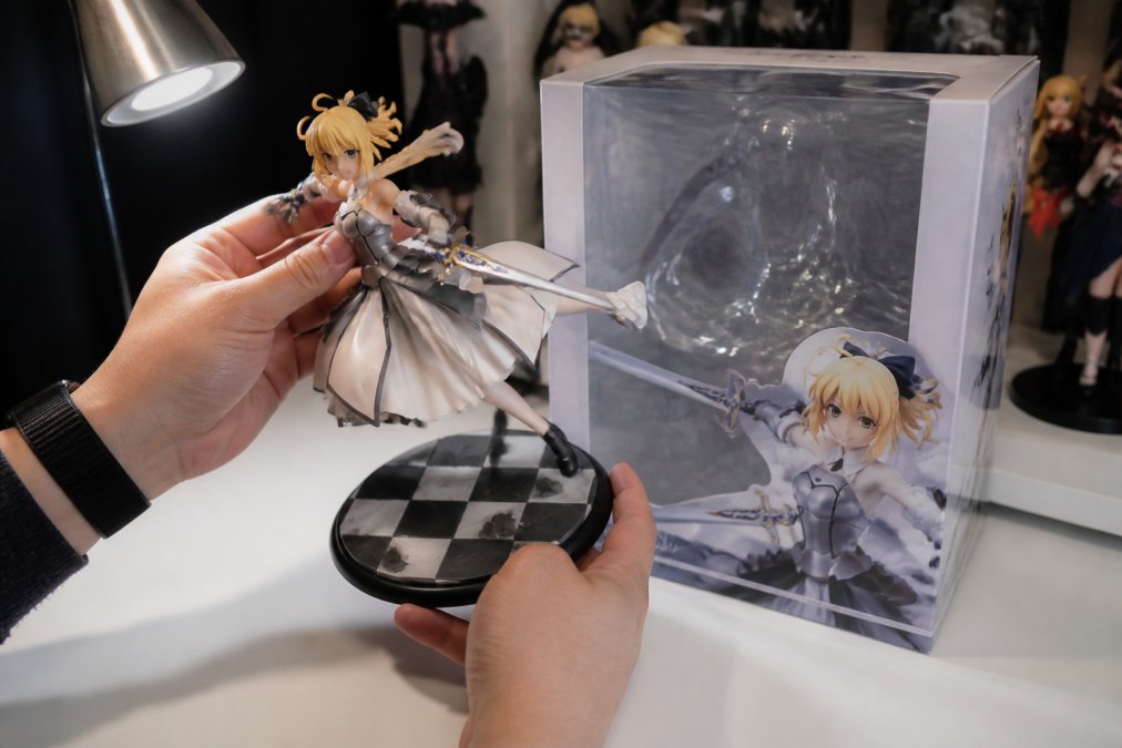 Collector inspecting a detailed anime figure, highlighting the paint finish for a kotobukiya vs good smile comparison.