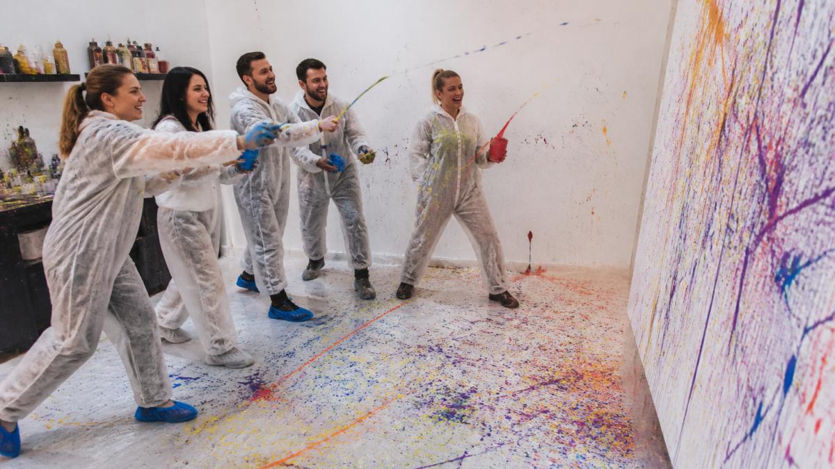 Eine Gruppe lacht beim Action-Painting, eines der kreative geburtstagsgeschenke wien für Paare und Gruppen.