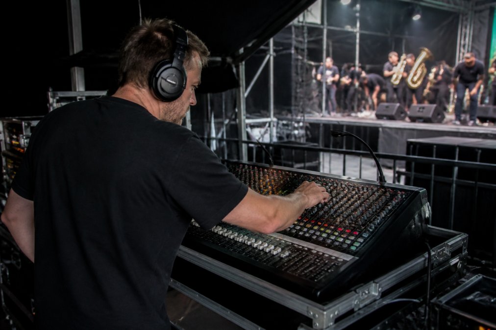 Geluidstechnicus achter mengpaneel tijdens soundcheck, concentratie op geluidsinstallatie met zichtbare apparatuur en koptelefoon
