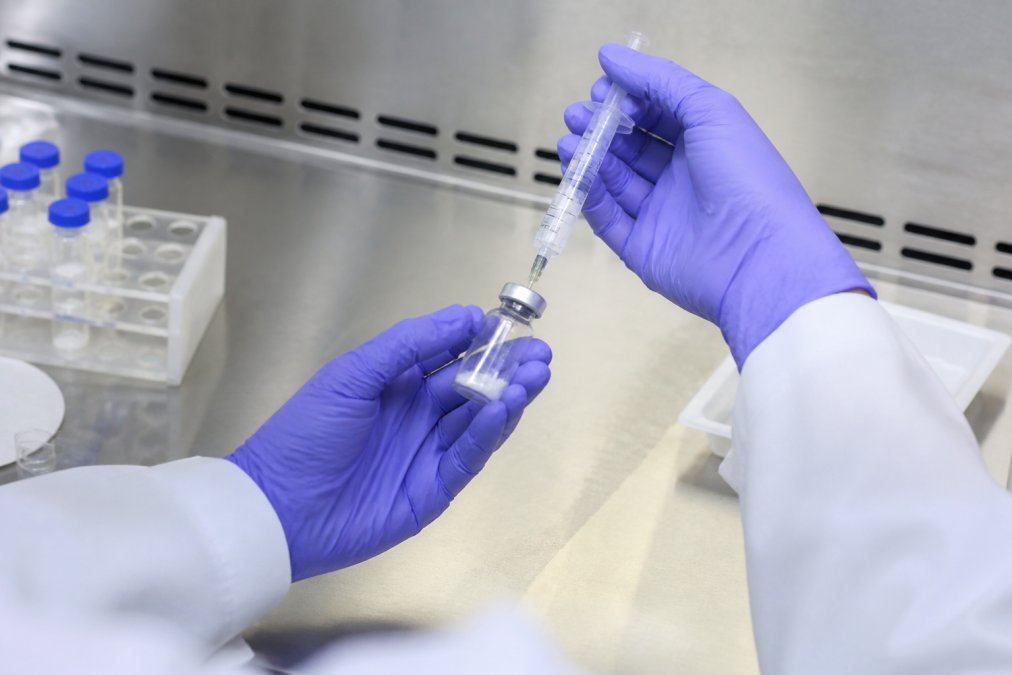 Close-up van handen die een gelyofiliseerd peptidemonster voorzichtig oplossen met bacteriostatisch water in een steriele omgeving